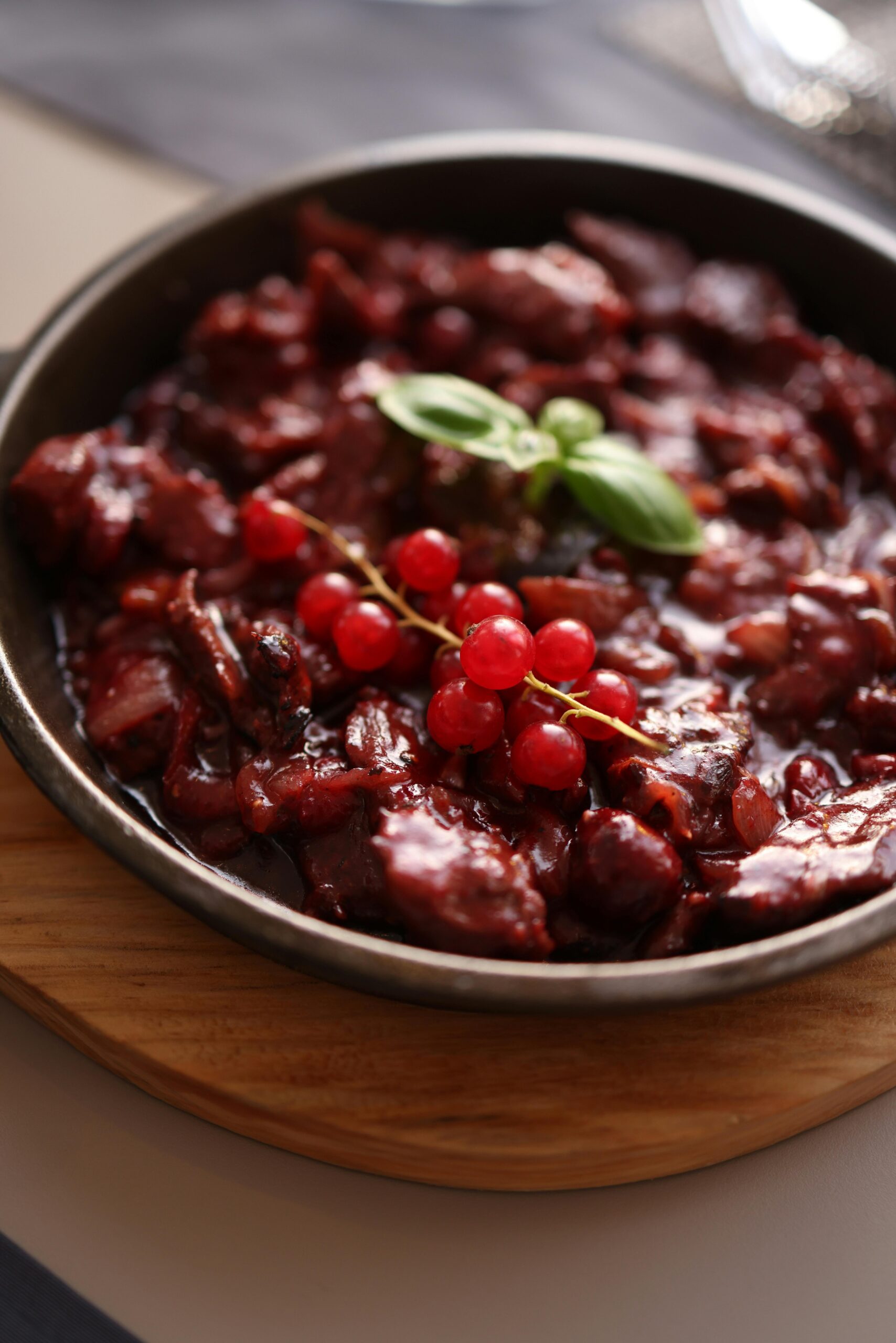 A mouthwatering beef stew with cranberries garnished with basil in a rustic bowl, perfect for a cozy meal.